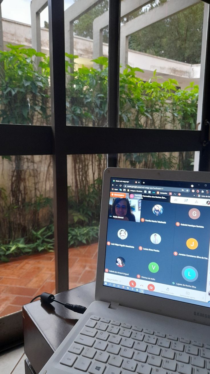 an open laptop computer sitting on top of a wooden table next to a large window