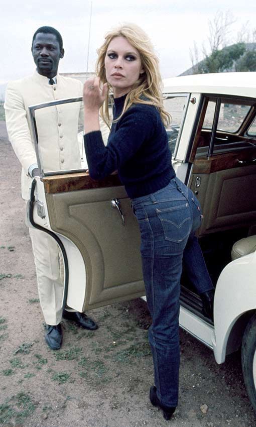 a woman leaning on the door of a car with a man standing next to her