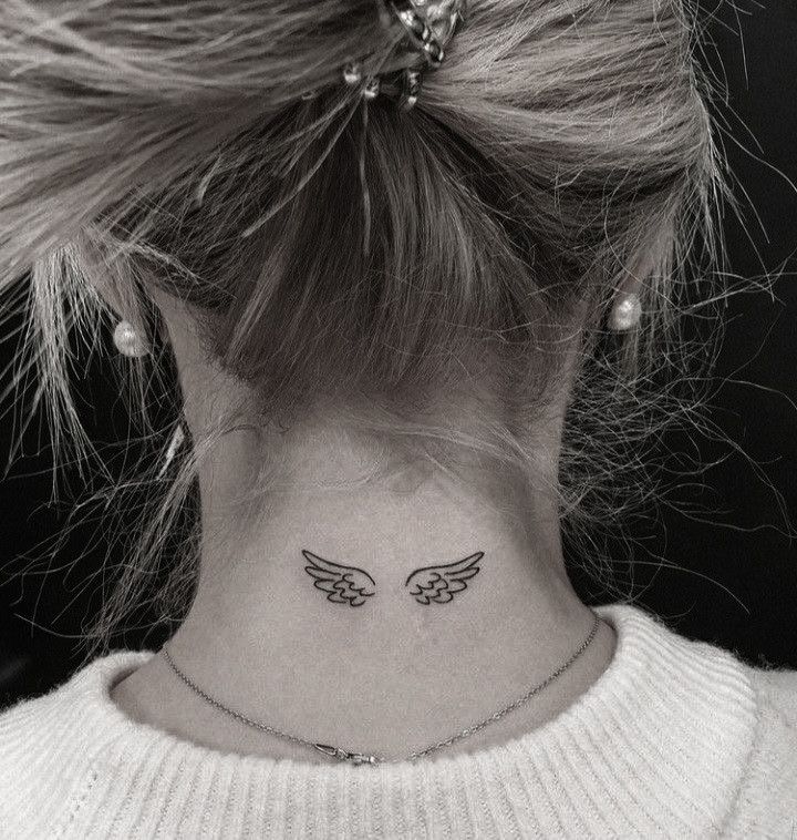 a woman's neck with angel wings tattoo on her left side ribcage