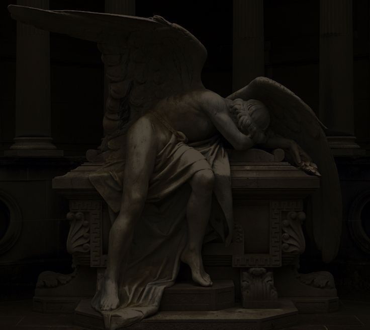 an angel statue laying on top of a stone bench