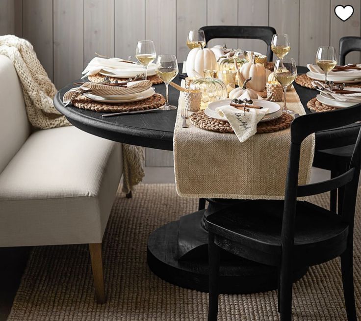 a dining room table with plates and glasses on top of it, next to a couch