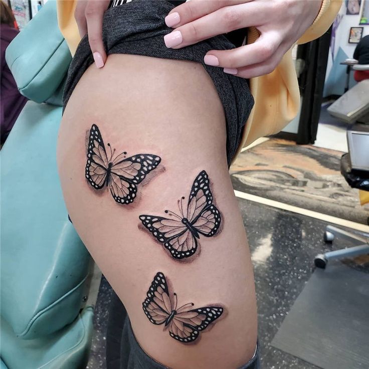 a woman's thigh with three butterflies tattooed on the side of her leg,