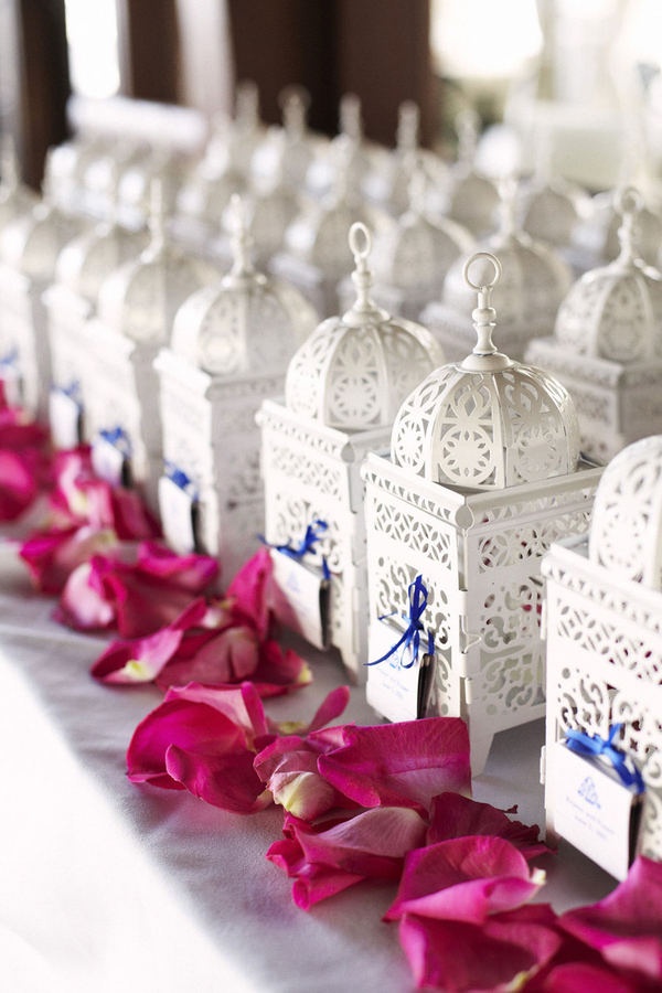 there are many small white cages with pink flowers on the table next to each other