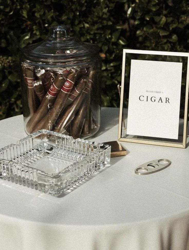 there is a glass jar with cigars in it and a sign on the table