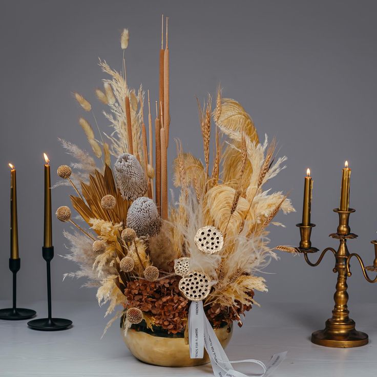 a vase filled with lots of different types of flowers and candles next to each other