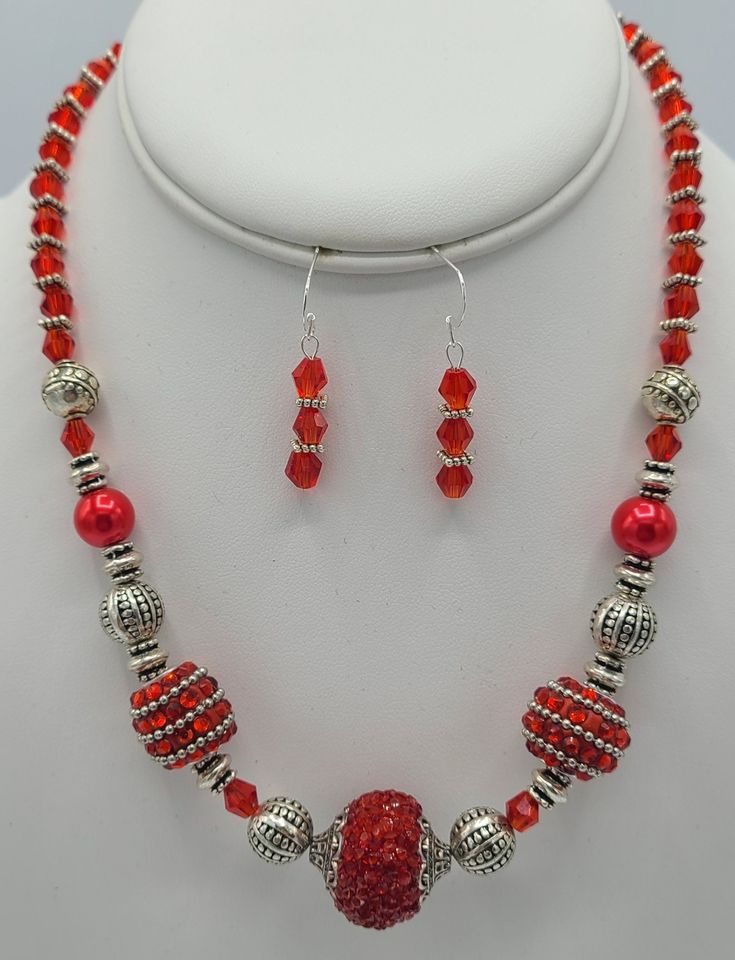 This 18 inch necklace is made from red crystal beads, various types of silver metal beads and bedazzled red beads.  It is completed with a sterling silver jump ring and a sterling silver lobster claw clasp.  The matching earrings are made with 3 of the red crystal beads with silver spacer beads in between and hang a total of 1 1/2 inches in length.   Each earring has a sterling silver earring wire. Red Faceted Beads Jewelry For Christmas, Red Round Beads Jewelry For Christmas, Red Beaded Christmas Jewelry, Adjustable Red Jewelry With Silver Beads, Red Spacer Beads Jewelry Gift, Red Spacer Beads Jewelry As Gift, Red Crystal Beaded Necklaces With Round Beads, Red Beaded Necklaces With Silver Beads As Gift, Red Beaded Sterling Silver Necklaces