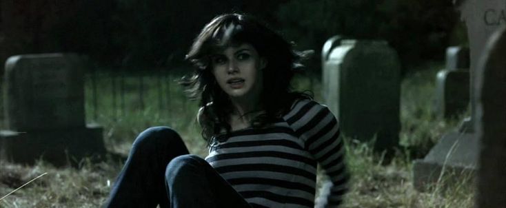 a woman sitting on the ground in front of graves