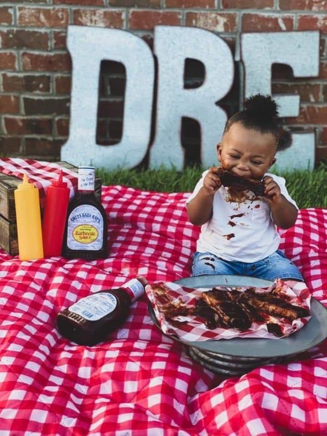 a little boy sitting on top of a red and white checkered blanket eating food