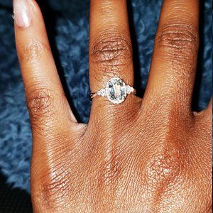 a woman's hand with a diamond ring on top of her thumb and the middle finger