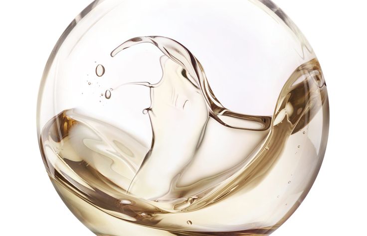 a wine glass filled with liquid on top of a white table