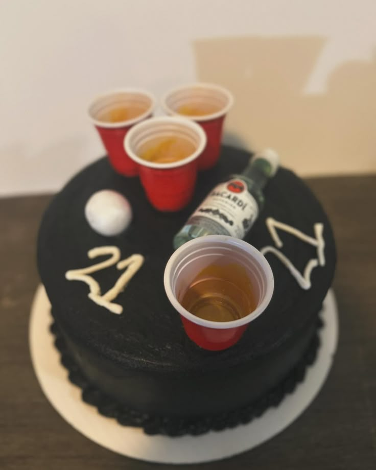 there is a cake with cups and a bottle on it