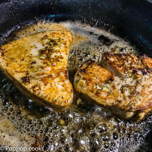 two pieces of chicken cooking in a skillet with some oil on the stove top