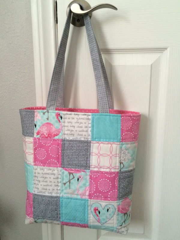 a pink and blue patchwork bag hanging on a door