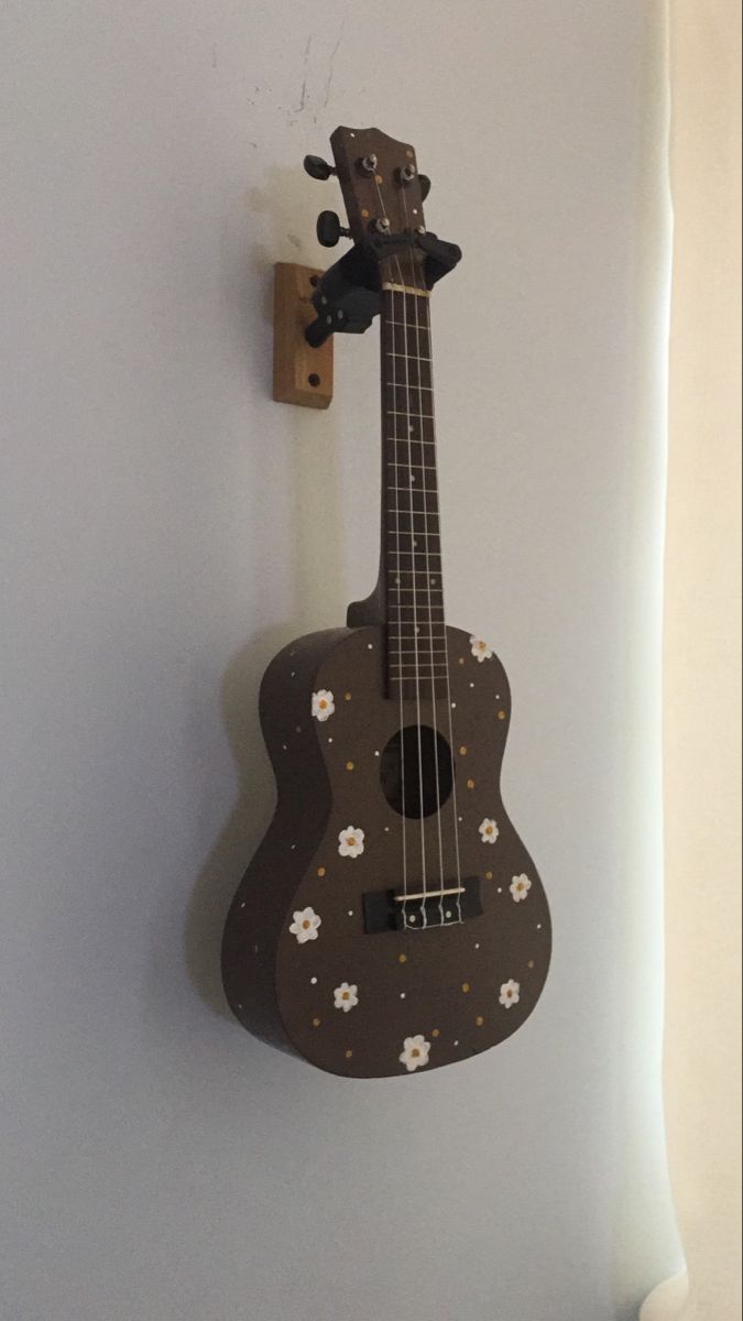 a wooden ukulele hanging on the wall next to a light switch cover with flowers