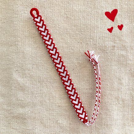 a red and white piece of fabric with hearts on the side, next to a pair of scissors