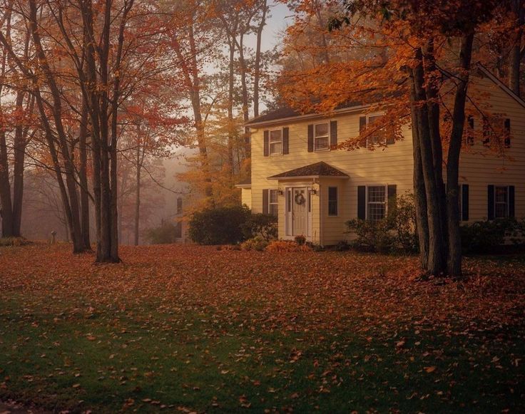 a white house surrounded by trees in the fall