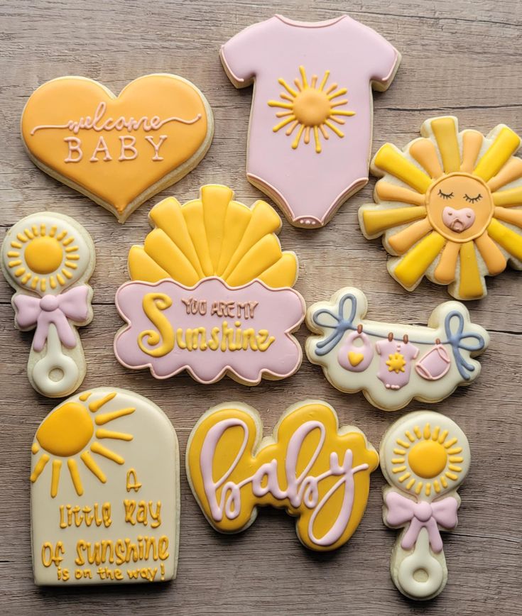 some cookies that are on top of a wooden table with baby's names and sunflowers