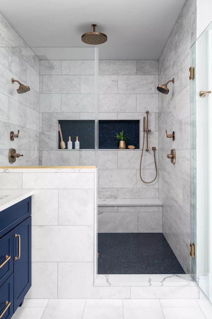 a walk in shower sitting next to a blue cabinet and white counter top with gold handles