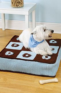 a small white dog sitting on top of a blue and brown blanket in a room