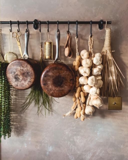 several cooking utensils hanging on a wall with garlic, mushrooms and other spices