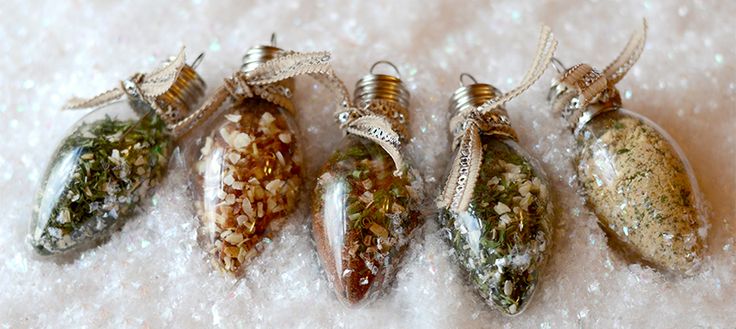 three ornaments are sitting on the snow covered ground, one is filled with tiny shells