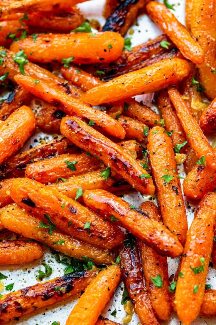 some cooked carrots on a white plate with parsley sprinkled around them