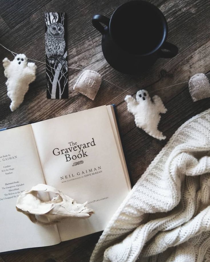 an open book sitting on top of a wooden table next to halloween decorations and candles