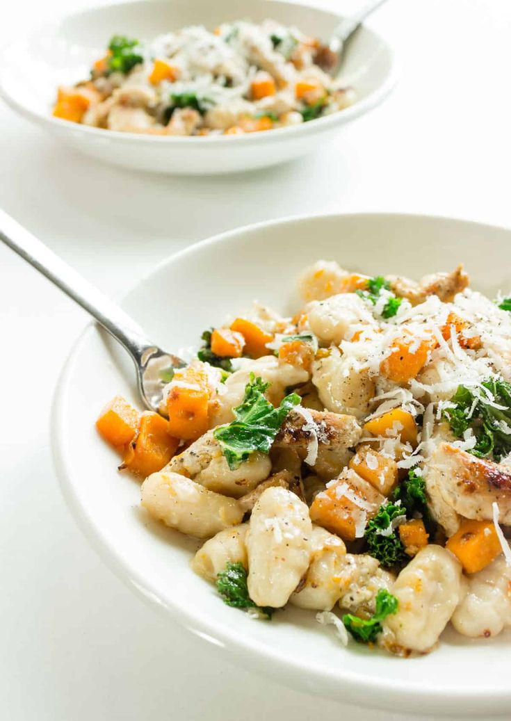 two white bowls filled with food on top of a table