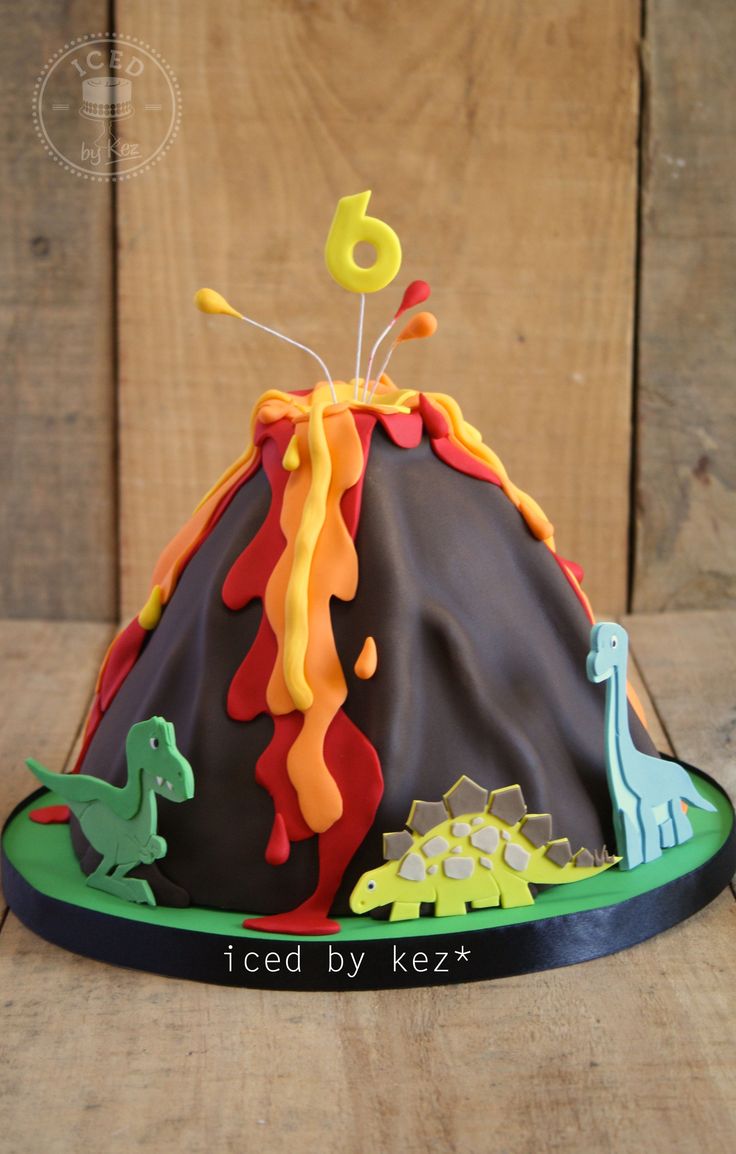 a birthday cake that is shaped like a volcano with dinosaurs on it and the number six