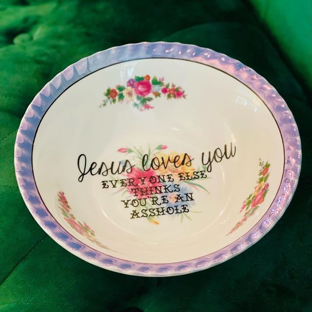 a bowl with the words jesus loves you on it and flowers in purple, pink and green