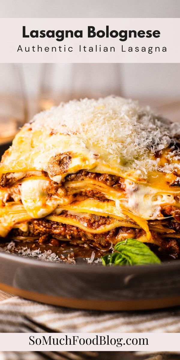 lasagna bolognaese with cheese and spinach in a black plate on a wooden table