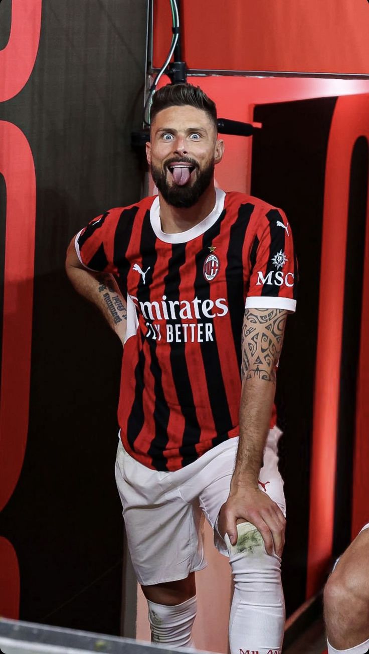 a man with his tongue out standing in front of a red and black wall