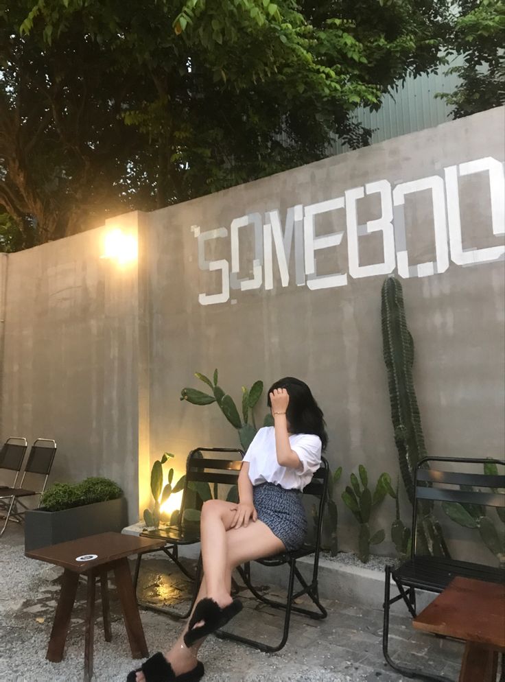 a woman sitting on a chair in front of a wall with some writing on it