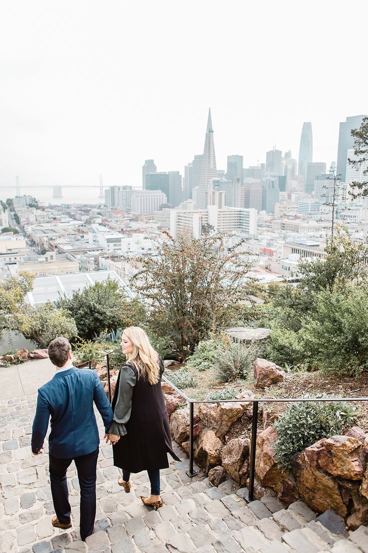 a man and woman walking up some stairs in front of the cityscape on a cloudy day