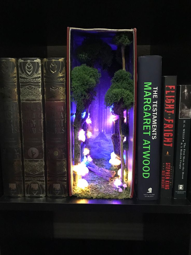 a book shelf filled with books and fake trees on top of each other in front of a row of books