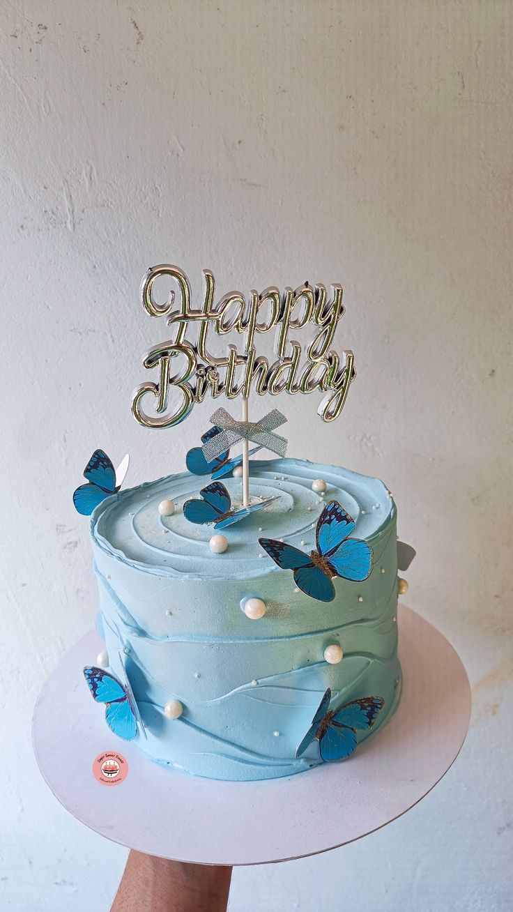 a blue birthday cake with butterflies on it