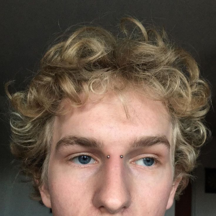 a young man with curly hair and blue eyes looks at the camera while wearing a tie