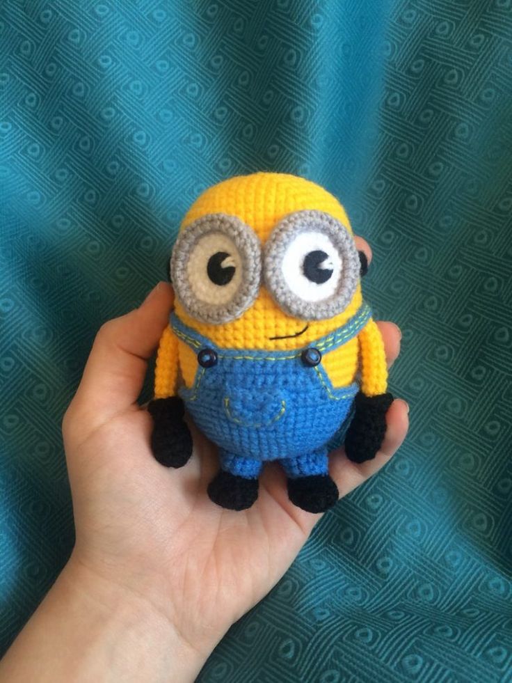 a hand holding a small yellow and blue toy