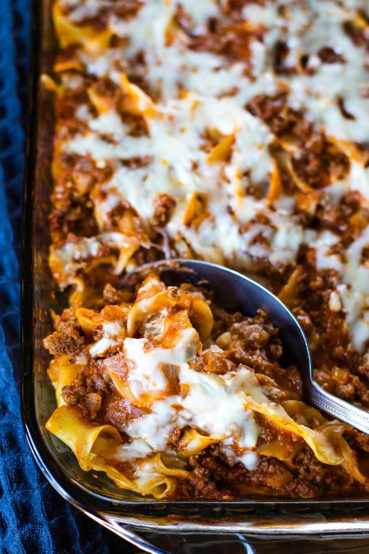 a casserole dish with meat, cheese and sauce in it on a blue towel