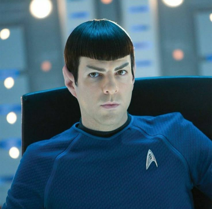 a man sitting in a chair with a star trek uniform on and looking at the camera