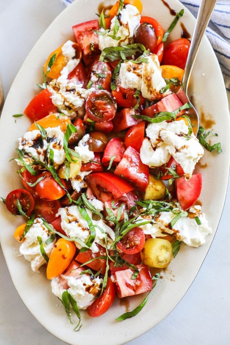 a white plate topped with tomatoes and feta cheese