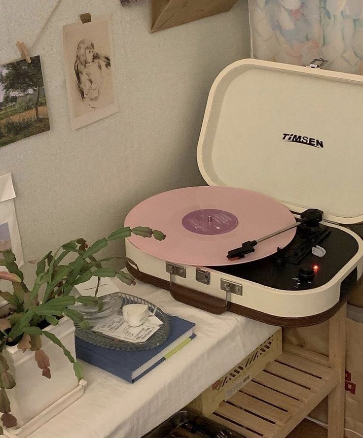 a record player sitting on top of a table next to a potted plant