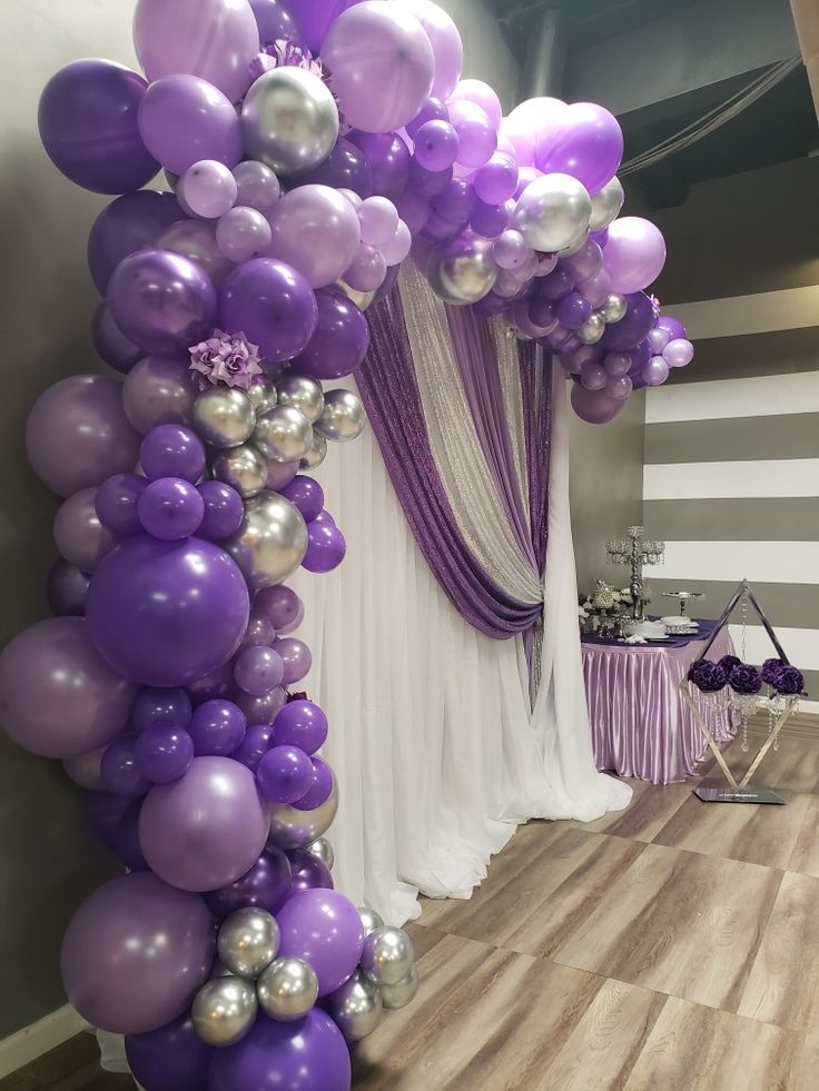 the balloon arch is decorated with purple and silver balloons