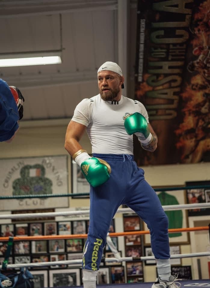 a man standing in a boxing ring wearing green gloves