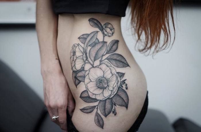 a woman's stomach with a flower tattoo on her lower body and the bottom part of her abdomen