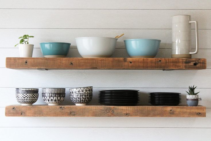 the shelves have bowls and cups on them, along with mugs that are sitting on top of each other