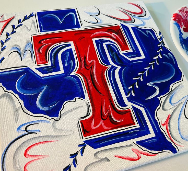 a red, white and blue painted letter t next to a toothbrush on a table