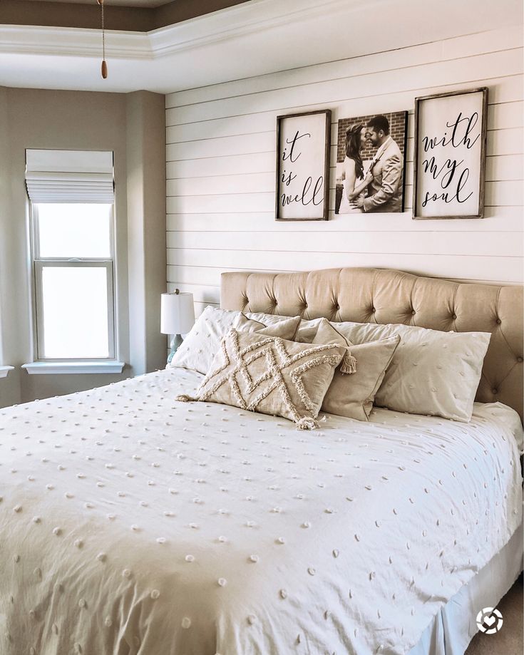 a bed with white sheets and pillows in a bedroom next to two pictures on the wall