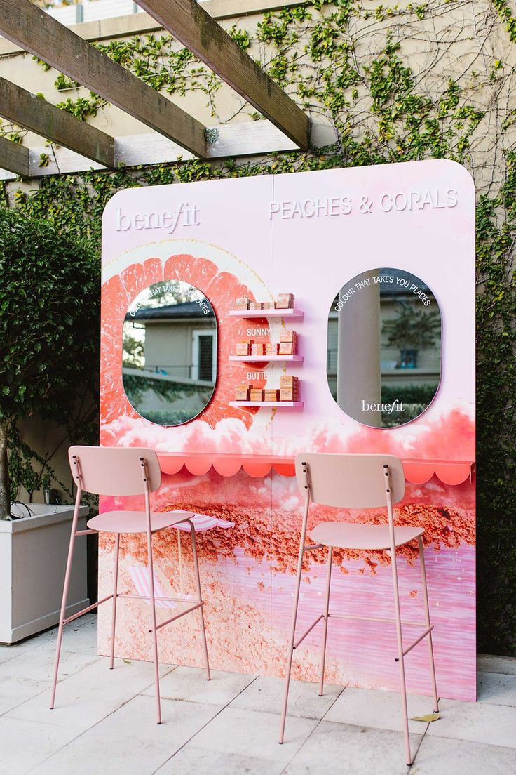 two chairs sitting in front of a pink counter with mirrors on it's sides