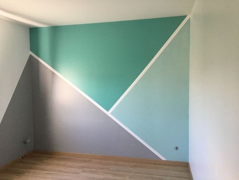 an empty room painted in shades of blue and green with wood flooring on the side